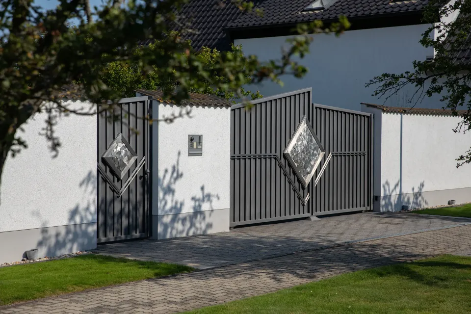 Toranlage mit Pforte und Rautenornamenten vor weißer Mauer