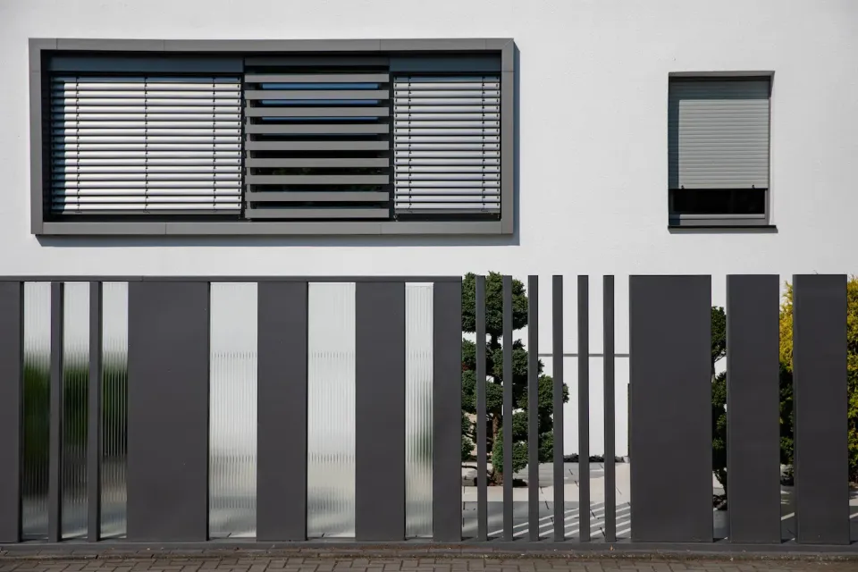 Zaun mit rhythmischen Stäben vor einem modernen Haus