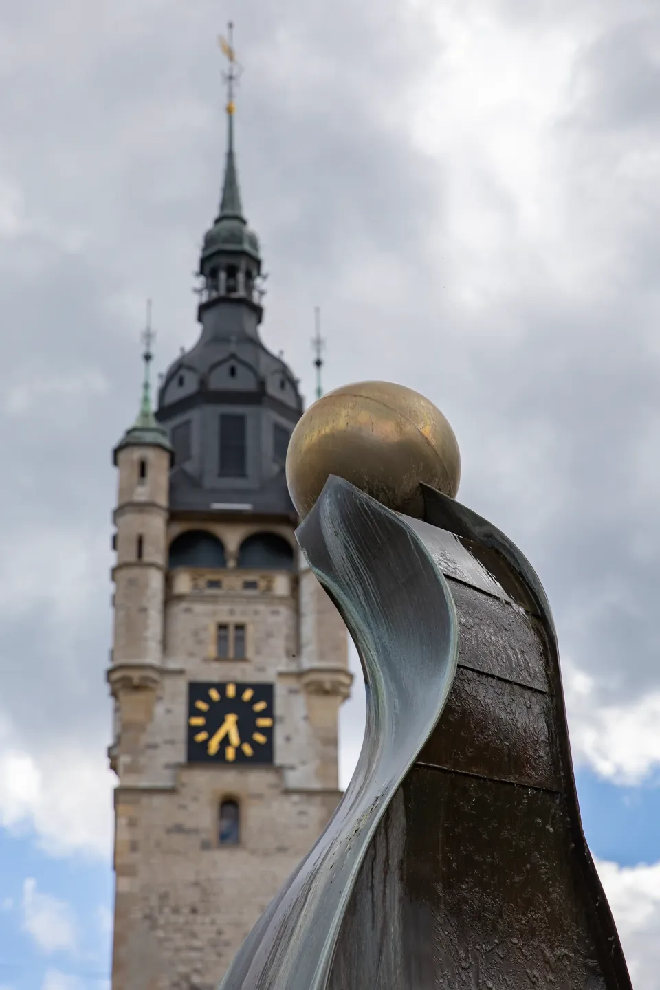 Zwei Bronzefiguren mit Kugeln vor blauem Himmel