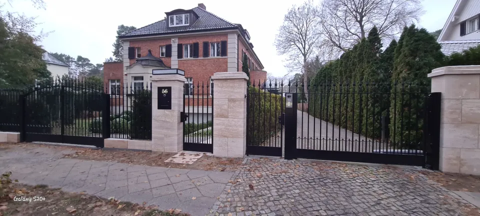 Zaunanlage mit Pfeilern und Leuchten vor einer Villa